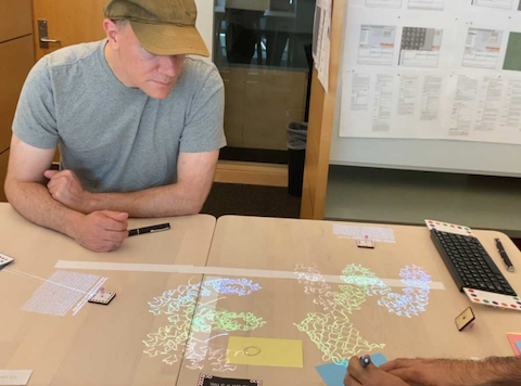 A person at  a table with projected images, coloured tiles and a keyboard